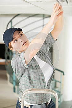 Woman on ladder fitting light bulb in new house