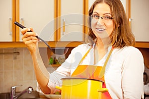 Woman with ladle and pot in kitchen