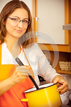 Woman with ladle and pot in kitchen