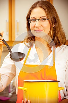 Woman with ladle and pot in kitchen