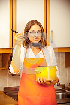 Woman with ladle and pot in kitchen