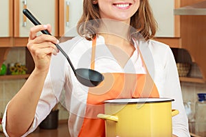 Woman with ladle and pot in kitchen