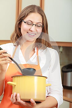 Woman with ladle and pot in kitchen