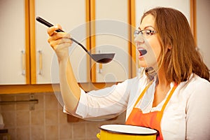 Woman with ladle and pot in kitchen