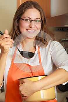 Woman with ladle and pot in kitchen