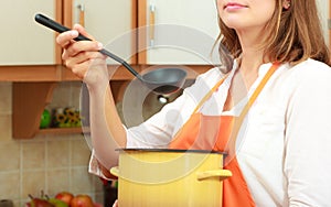 Woman with ladle and pot in kitchen