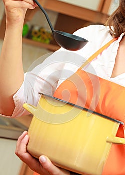 Woman with ladle and pot in kitchen