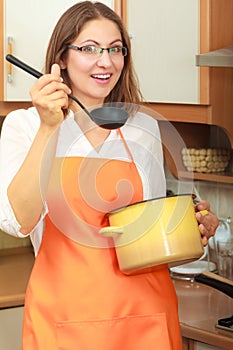 Woman with ladle and pot in kitchen