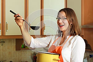 Woman with ladle and pot in kitchen