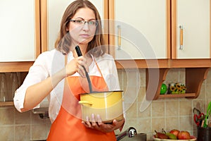 Woman with ladle and pot in kitchen
