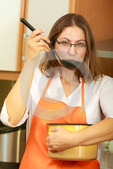 Woman with ladle and pot in kitchen