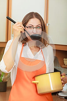 Woman with ladle and pot in kitchen