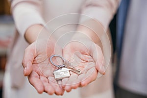 Woman landlord's hand holds keys symbolizing property deal achievement. Real