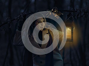 Woman with a lantern in the forest at night