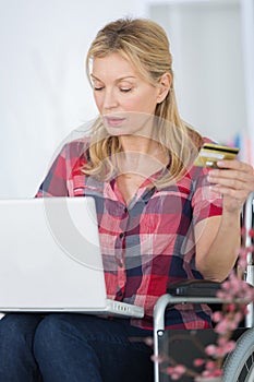 woman with laptop and card in studio isolated orange background