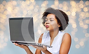 Woman with laptop computer sending kiss to someone