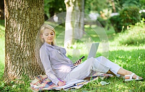 Woman with laptop computer work outdoors lean on tree trunk. Girl work with laptop in park sit on grass. Natural