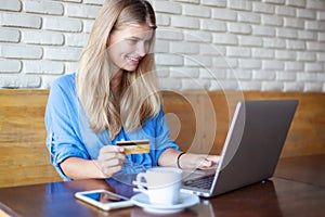 Woman with laptop and credit card in cafe . Online payment, digital banking. Young girl shopping