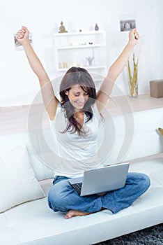 Woman with laptop on crossed legs making gesture triumph