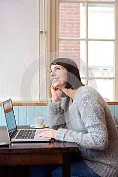 Woman with laptop daydreaming