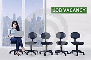 Woman with laptop and empty chair in office