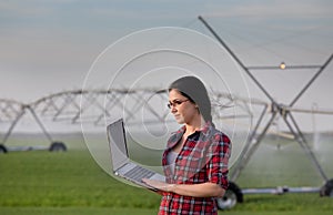 Woman with laptop on irrigated field