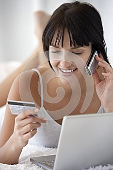 Woman With Laptop Making Credit Card Purchase On Cellphone