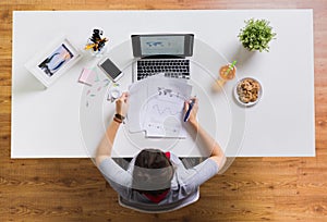 Woman with laptop and papers at office table