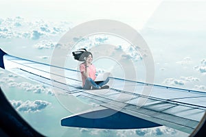 Woman with laptop and phone sitting on plane wing