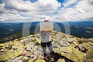 Woman with laptop standing on a stone