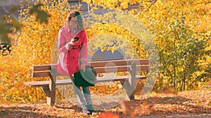 Woman with a laptop texting on the smart phone in a autumn park