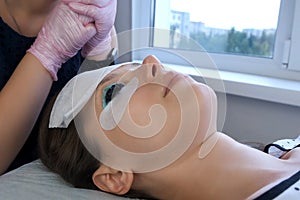 Woman on lash lifting laminating painting procedure in beauty clinic, closeup.