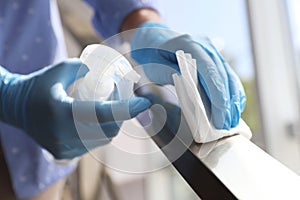 Woman in latex gloves cleaning railing with wet wipe and detergent, closeup