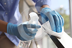 Woman in latex gloves cleaning railing with wet wipe and detergent, closeup