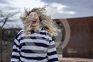 A woman laughing with her hair blowing in the wind outdoors