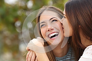 Woman laughing with perfect teeth while a friend is kissing her photo