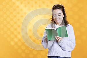 Woman laughing while reading funny book, isolated over studio background
