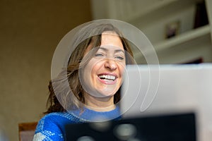 Woman laughing to herself as she reads media on her laptop computer