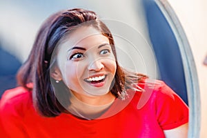 Woman laughs and looks at the reflection in a distorted mirror room