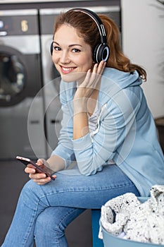 woman in laundrette listening to music to pass time