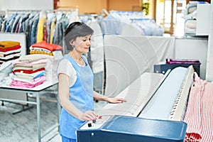 Woman Laundry worker pats the linen on the automatic machine