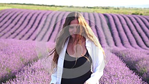 Woman in lavender field - happy lady in hat enjoys sunny day, wandering in lavender field, appreciating nature. Girl