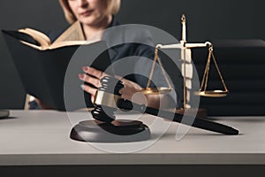 Woman lawyer reading professional books in office. Wooden gavel and libra on the desk.