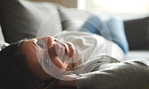 Woman laying on back with head tilted back smiling.