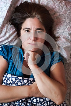 Woman laying in bed with a worried and sad expression - Sickness, depression, anxiety