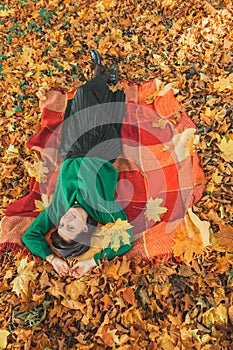 woman laying on the blanket on the ground at autumn public park