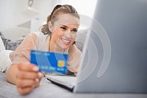 Woman laying on divan with laptop and credit card