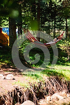 woman laying down in hammock in the forest tent on background