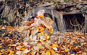 Woman laying down on the pile of leafs and playing.