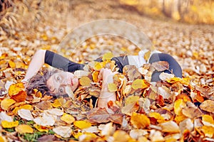 Woman laying down on the pile of leafs and playing.